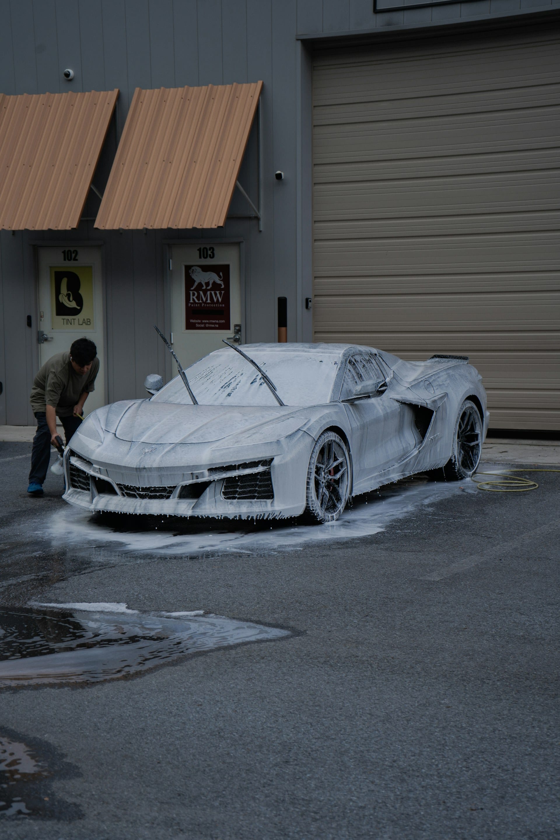 Detailer applying a dense foam wash to a vehicle exterior