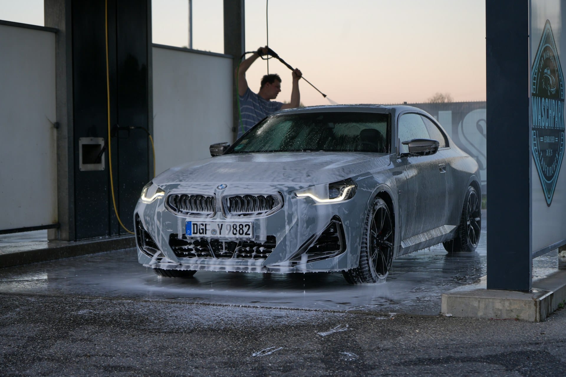 Silver car being hand-washed at a home driveway