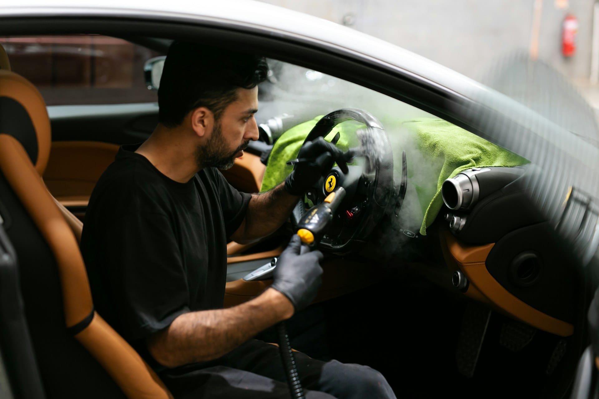 Professional detailer steam cleaning a vehicle interior