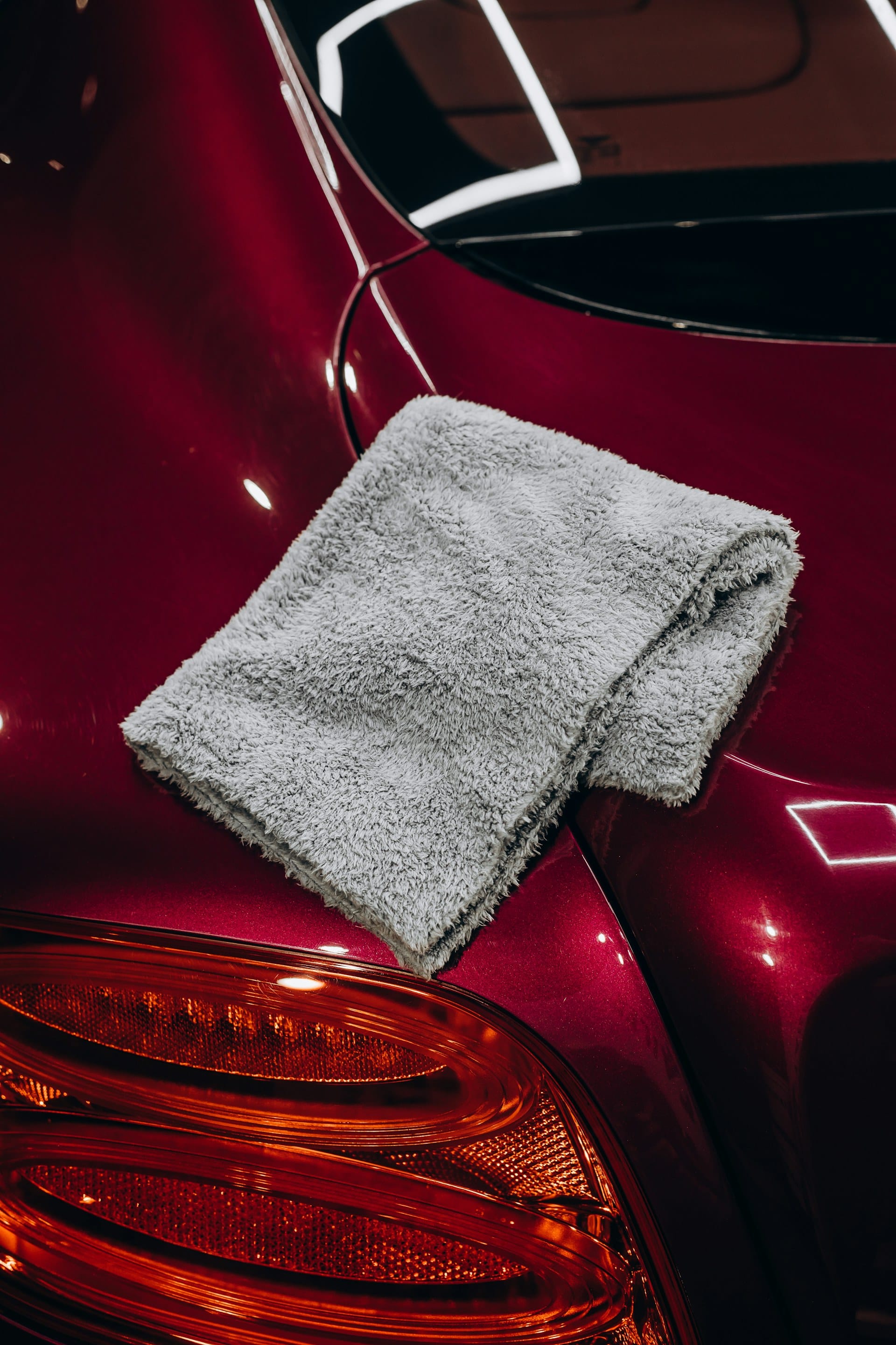 Hand drying a red car with microfiber