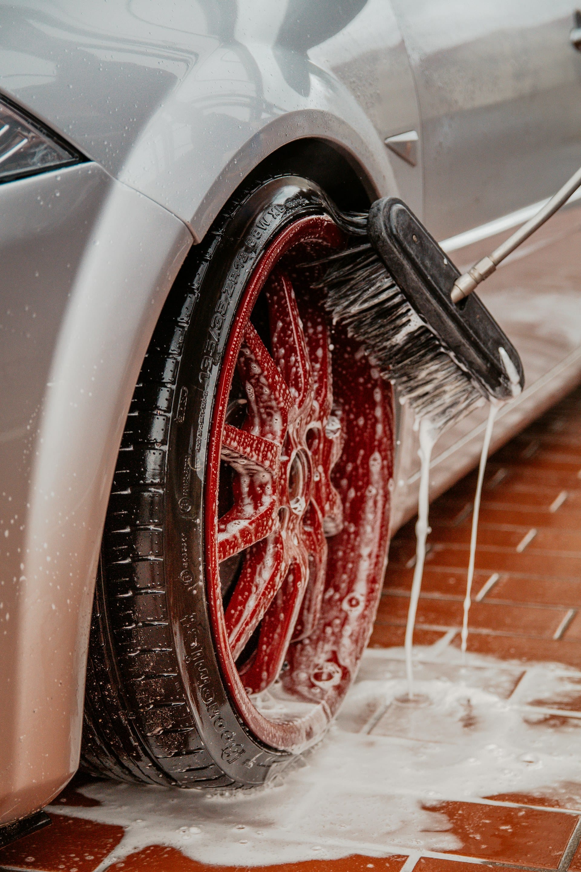 Detailer hand cleaning an alloy wheel and tire